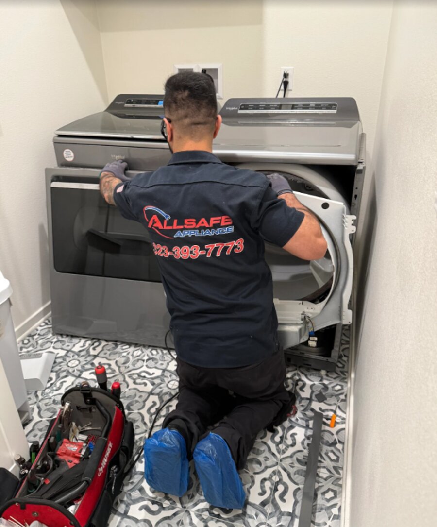 Allsafe technician repairing a washer and dryer in a customer's home