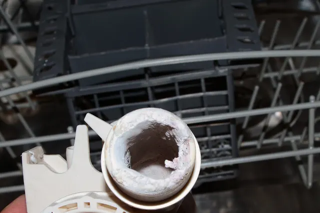 Dishwasher part coated in white hard water mineral deposits