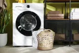 Front-load washing machine that won't start in a laundry room with a basket of towels beside it