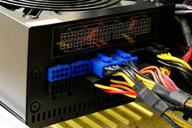 Close-up of a computer power supply with blue connectors and bundled multicolored wires